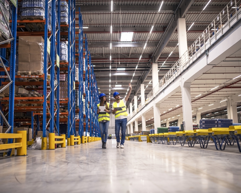distribution-warehouse-interior-with-workers-wearing-hardhats-reflective-jackets-walking-storage-area-788x631-1